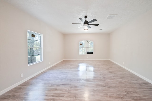 empty room with ceiling fan, a textured ceiling, and light hardwood / wood-style flooring