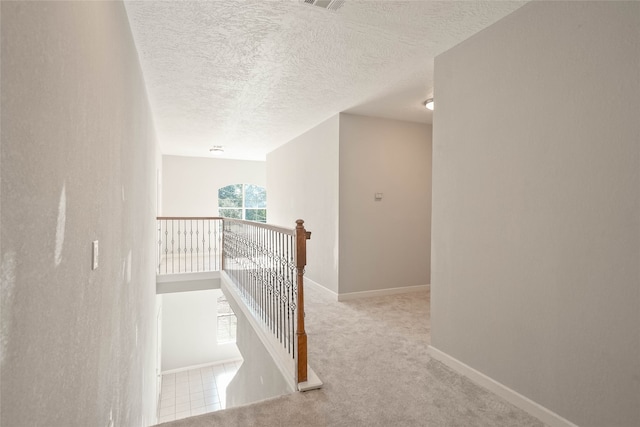 corridor with light carpet and a textured ceiling