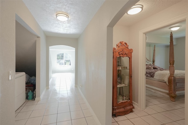 hall featuring light tile patterned floors and a textured ceiling