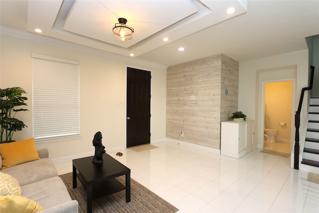 living room with a raised ceiling, light tile patterned floors, and crown molding