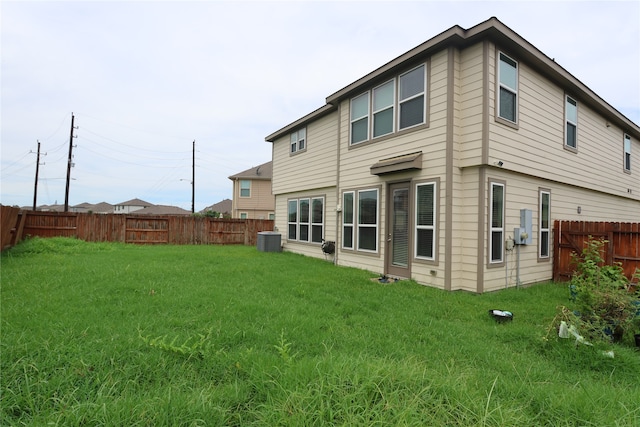 rear view of house with a lawn and central air condition unit