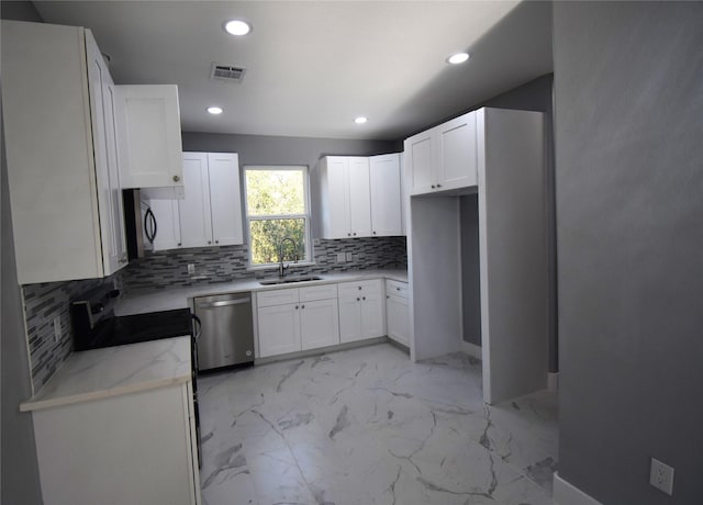 kitchen featuring light stone countertops, sink, stainless steel dishwasher, decorative backsplash, and white cabinets