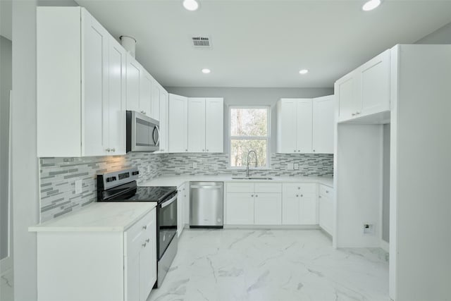 kitchen with sink, appliances with stainless steel finishes, tasteful backsplash, light stone countertops, and white cabinets