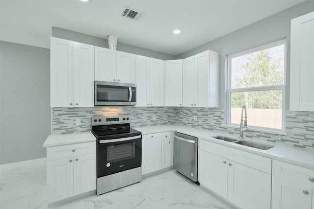 kitchen with stainless steel appliances, white cabinetry, sink, and backsplash