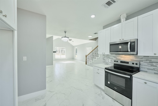 kitchen with white cabinetry, tasteful backsplash, lofted ceiling, and appliances with stainless steel finishes