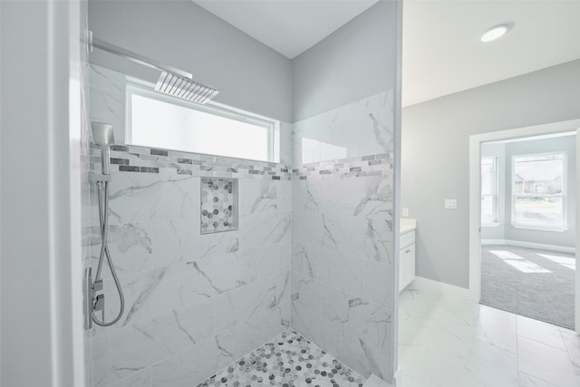 bathroom featuring a healthy amount of sunlight, vanity, and tiled shower