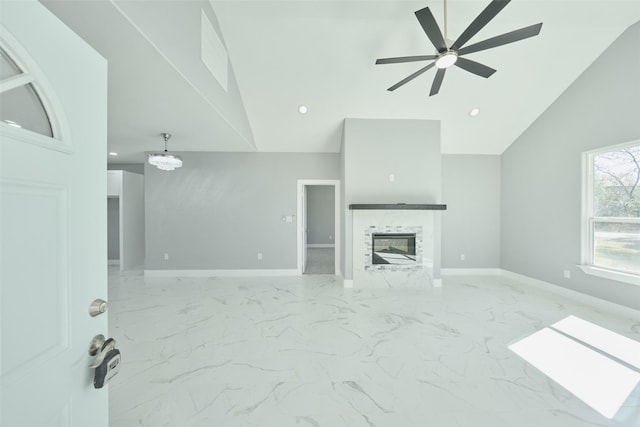 living room with high vaulted ceiling, ceiling fan with notable chandelier, and a fireplace