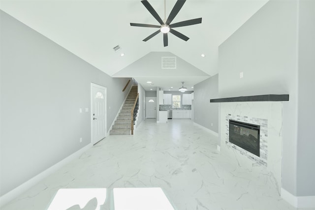 living room with a tiled fireplace, high vaulted ceiling, and ceiling fan