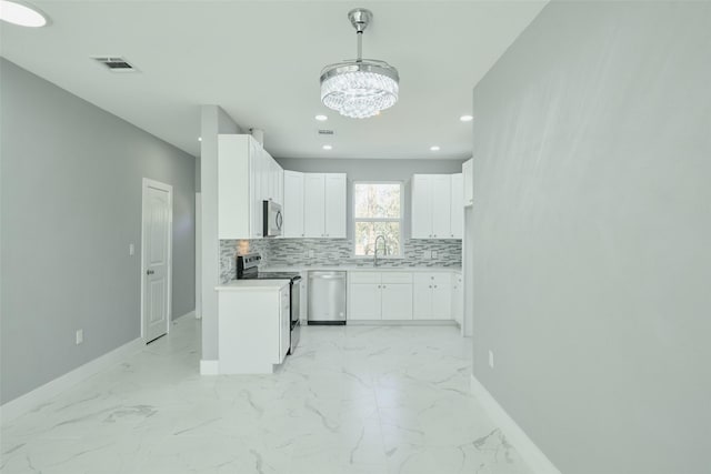 kitchen with tasteful backsplash, sink, white cabinets, hanging light fixtures, and stainless steel appliances