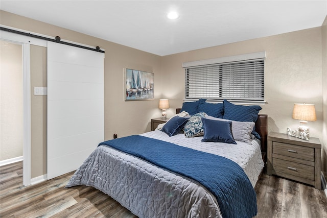 bedroom featuring hardwood / wood-style floors and a barn door