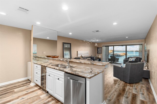 kitchen with light wood-type flooring, white cabinetry, stainless steel dishwasher, and sink