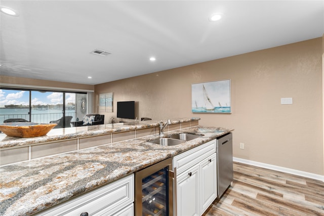 kitchen featuring light stone countertops, sink, dishwasher, light hardwood / wood-style floors, and wine cooler