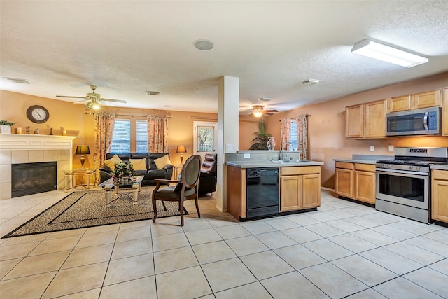 kitchen featuring a textured ceiling, stainless steel appliances, sink, light tile patterned floors, and a tiled fireplace