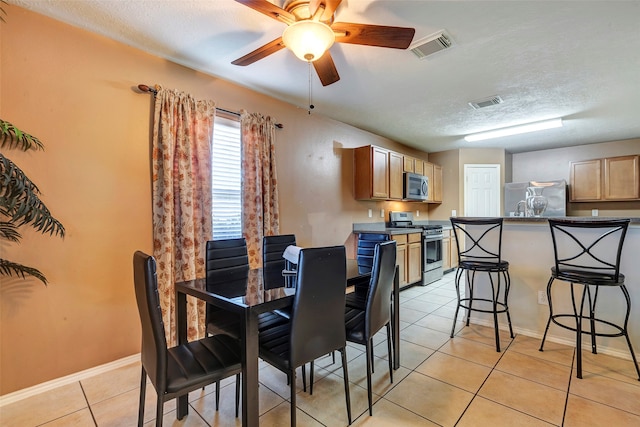 dining area featuring light tile patterned floors, a textured ceiling, and ceiling fan