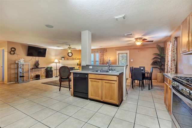 kitchen featuring stainless steel gas range oven, sink, a tile fireplace, light tile patterned floors, and black dishwasher