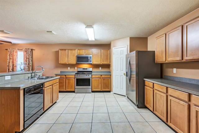 kitchen featuring sink, light tile patterned floors, stainless steel appliances, and a textured ceiling