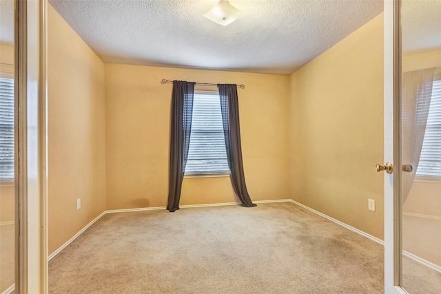 carpeted empty room featuring a textured ceiling