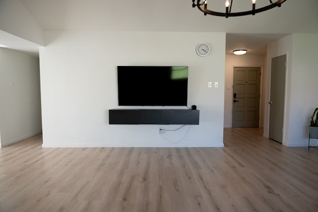 unfurnished living room with light hardwood / wood-style floors and an inviting chandelier