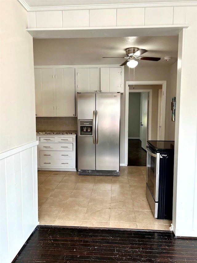 kitchen with backsplash, black / electric stove, stainless steel fridge, white cabinets, and light wood-type flooring