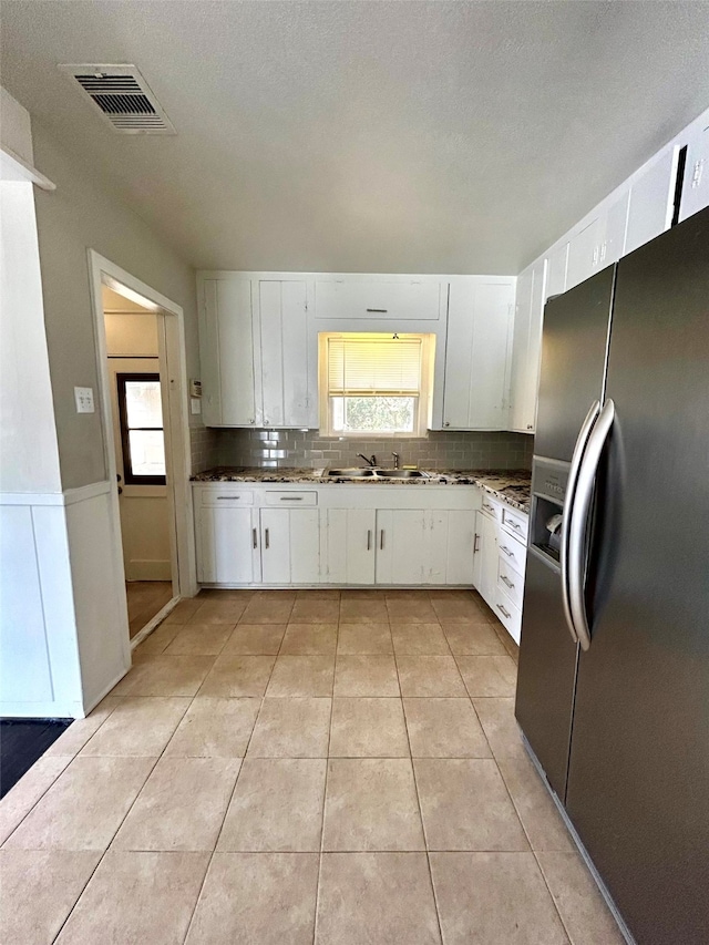 kitchen with decorative backsplash, stainless steel fridge with ice dispenser, white cabinetry, and sink