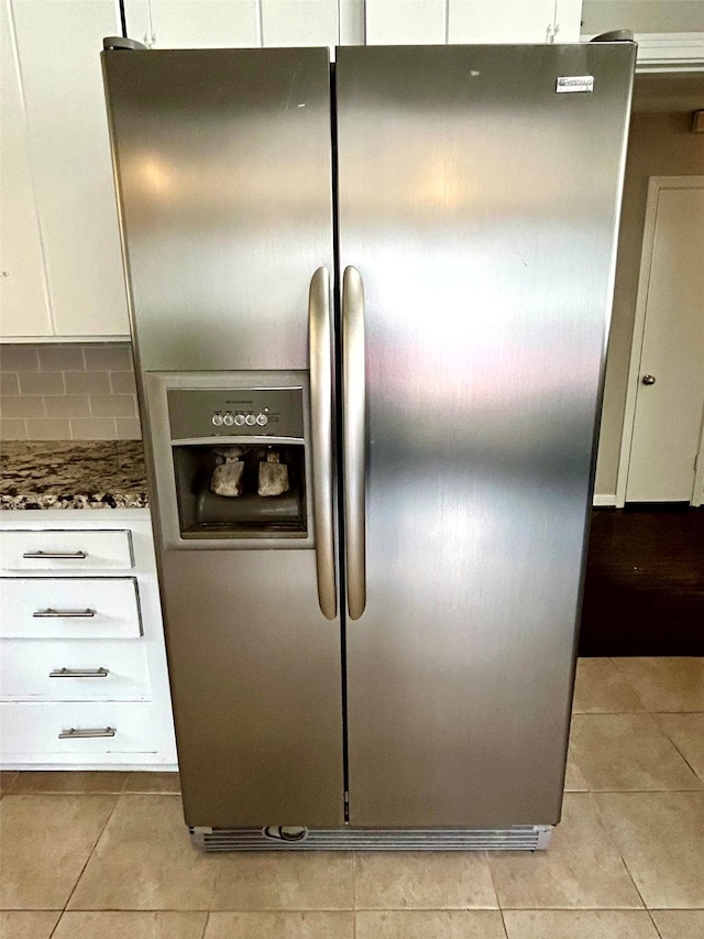 details featuring stainless steel refrigerator with ice dispenser, white cabinetry, and dark stone countertops