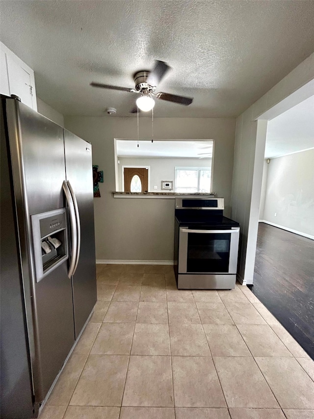 kitchen featuring ceiling fan, light tile patterned floors, a textured ceiling, white cabinets, and appliances with stainless steel finishes