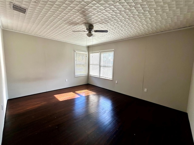 empty room with ceiling fan, dark wood-type flooring, and ornamental molding