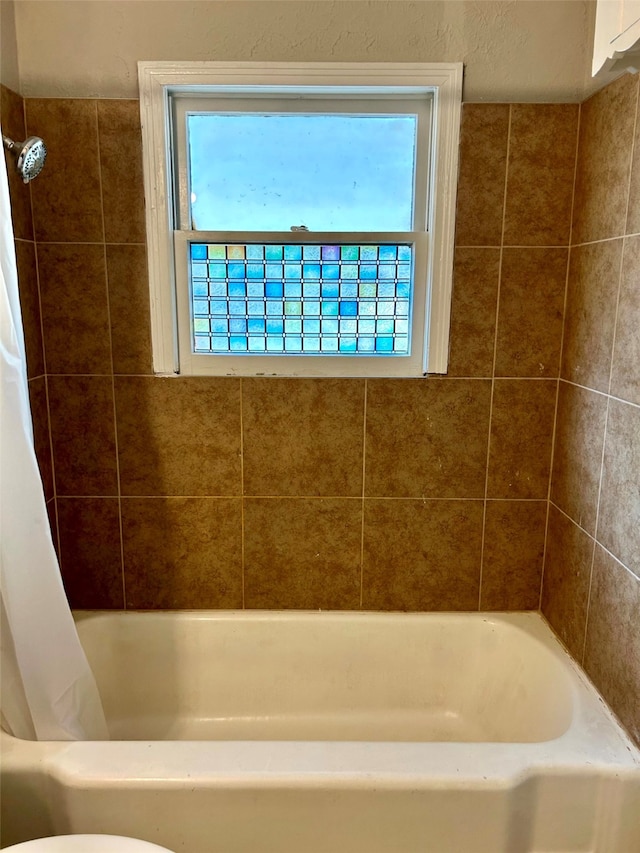 bathroom with plenty of natural light, shower / bath combination with curtain, and toilet