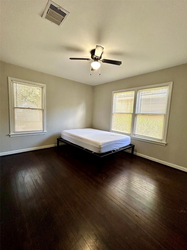 unfurnished bedroom featuring ceiling fan and dark hardwood / wood-style flooring