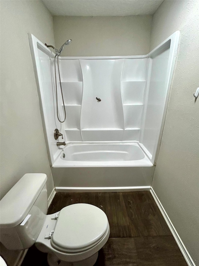 bathroom featuring hardwood / wood-style flooring, shower / bathtub combination, and toilet