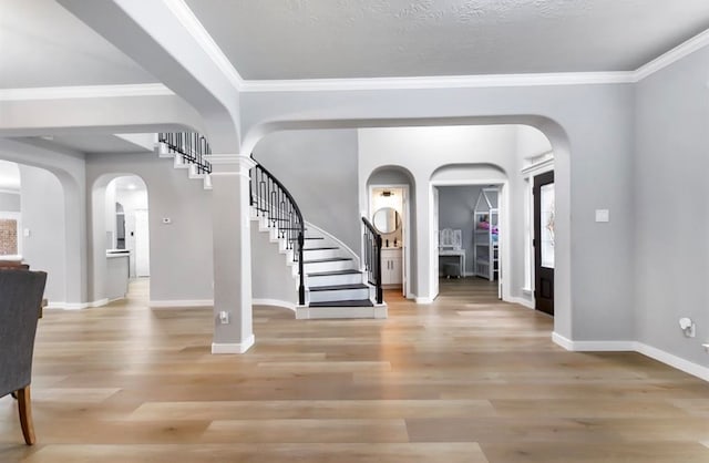 foyer with a textured ceiling, light hardwood / wood-style flooring, and ornamental molding