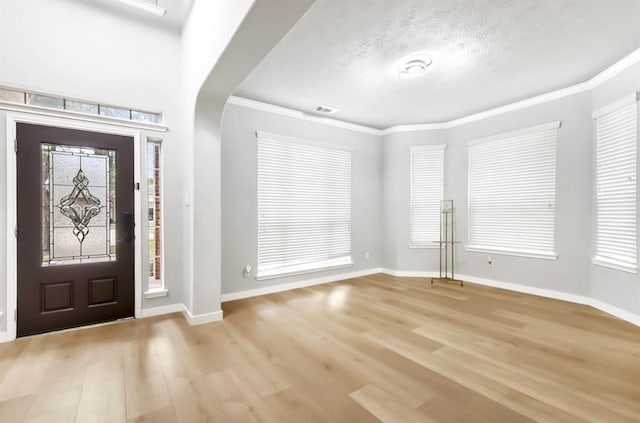 foyer with a textured ceiling, light hardwood / wood-style floors, and crown molding