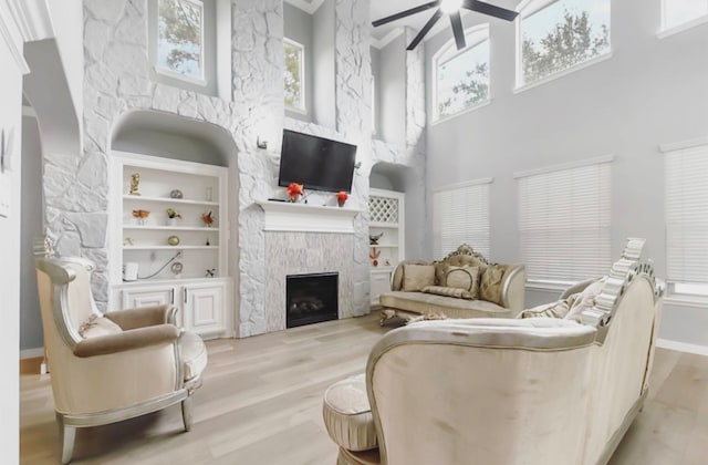 living room with a fireplace, plenty of natural light, a high ceiling, and light wood-type flooring