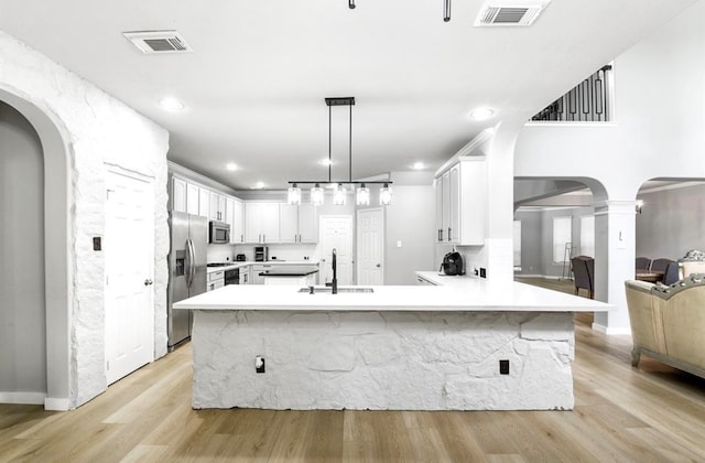 kitchen with sink, decorative light fixtures, light hardwood / wood-style floors, white cabinetry, and stainless steel appliances