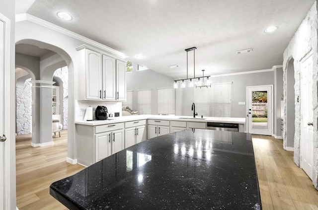 kitchen featuring kitchen peninsula, white cabinets, hanging light fixtures, and light wood-type flooring