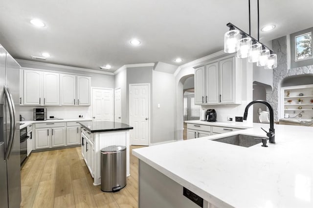 kitchen featuring white cabinetry, sink, a center island, decorative light fixtures, and light wood-type flooring