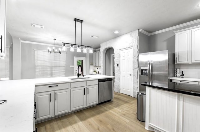 kitchen with sink, hanging light fixtures, light wood-type flooring, appliances with stainless steel finishes, and ornamental molding