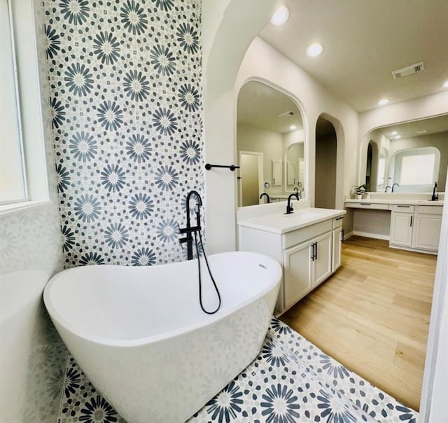 bathroom featuring vanity, a bath, tile walls, and hardwood / wood-style flooring