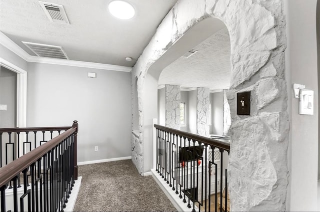 corridor featuring crown molding, a textured ceiling, and dark colored carpet