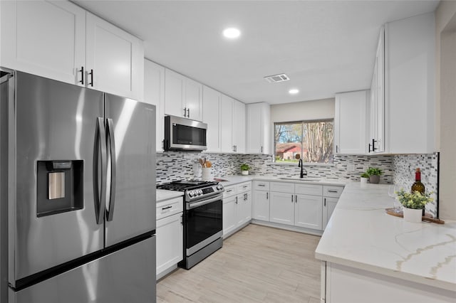 kitchen featuring white cabinets, sink, decorative backsplash, light stone countertops, and stainless steel appliances