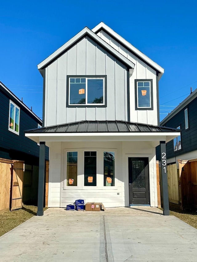 view of front of property with board and batten siding, a standing seam roof, and fence