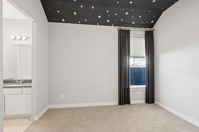 empty room with light carpet, vaulted ceiling, and sink