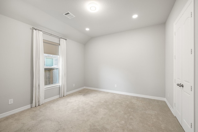 unfurnished room featuring light colored carpet and lofted ceiling