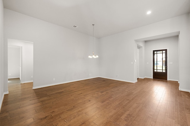 unfurnished room featuring a chandelier and dark hardwood / wood-style floors