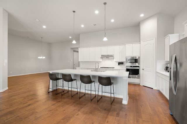 kitchen featuring white cabinets, appliances with stainless steel finishes, dark hardwood / wood-style floors, and an island with sink