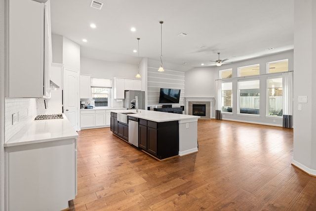 kitchen with light wood-type flooring, white cabinetry, a kitchen island with sink, and ceiling fan