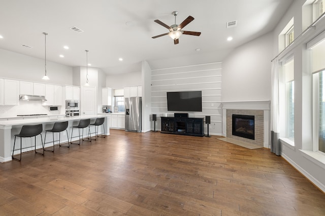 living room with plenty of natural light, ceiling fan, dark hardwood / wood-style flooring, and high vaulted ceiling