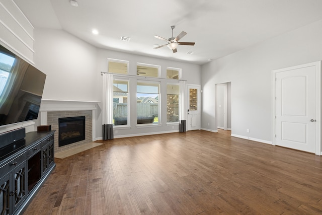 unfurnished living room featuring vaulted ceiling, dark hardwood / wood-style floors, a brick fireplace, and ceiling fan