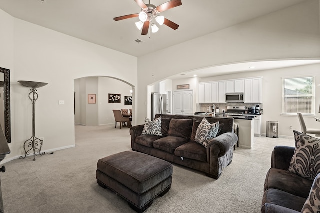 carpeted living room featuring ceiling fan and high vaulted ceiling