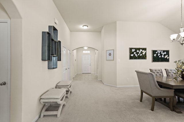 hallway featuring light carpet, lofted ceiling, and an inviting chandelier